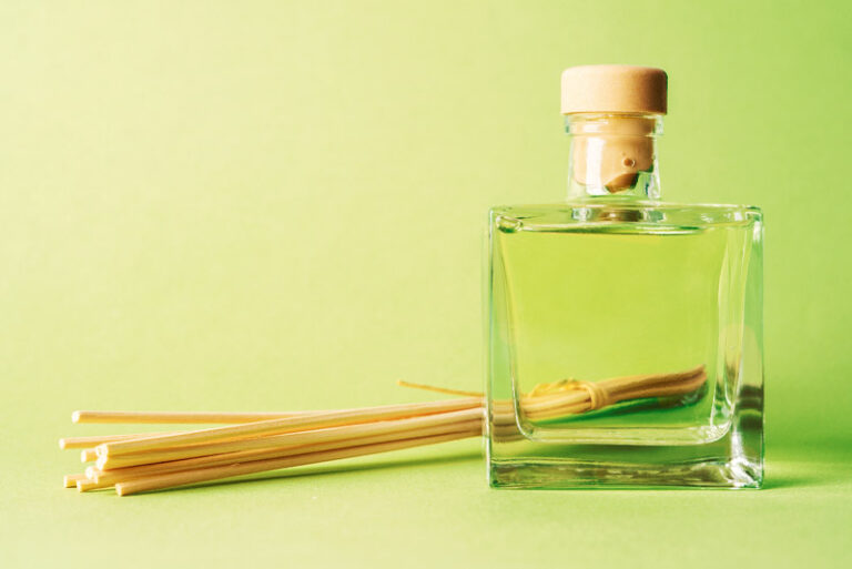 Aroma reed diffuser home fragrance with rattan sticks with glass bottle. Tropical green mood blank background.