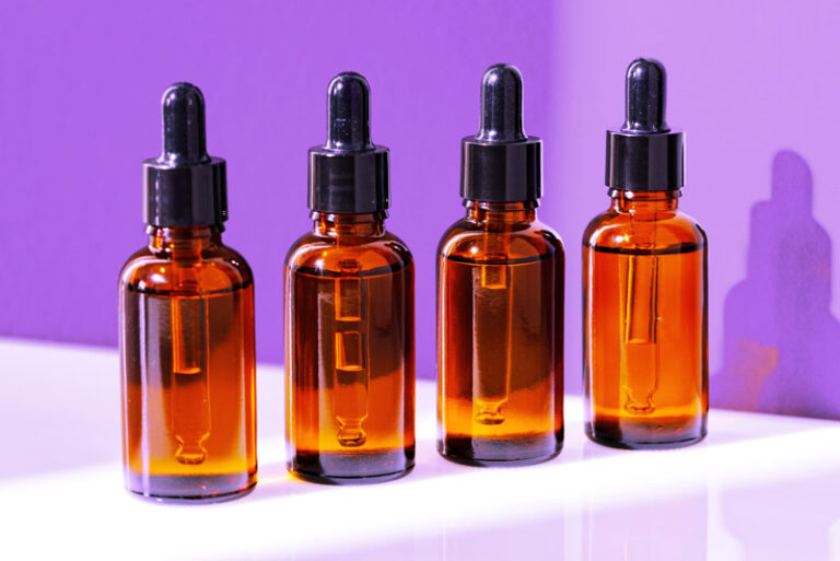 Bottle, vitamin capsules, spoon and leaves on white background, flat lay